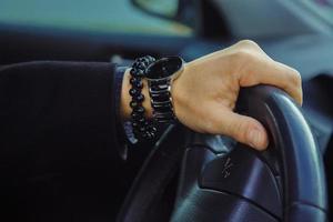 Color image of adult male hand with watch and bracelet in car photo