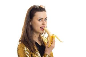 pretty young in golden jacket looking at the camera and eating a banana photo