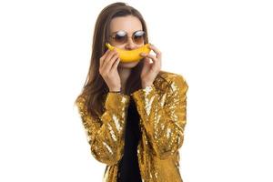 pretty elegant woman in golden jacket with banana photo