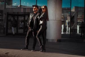 pareja de moda en trajes de cuero posando en la ciudad durante el día foto