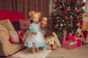 familia elegante alegre. mamá e hija en el árbol de Navidad foto