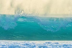 Image of wave breaking on the beach with flying spray and turquoise color photo