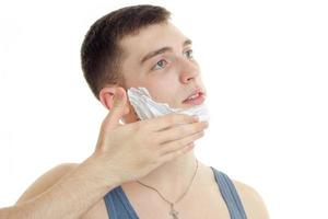 Portrait of a young guy who looks away and putting a beard foam photo