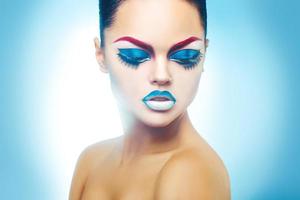 mujer seductora con piel sana y maquillaje sobre fondo azul foto