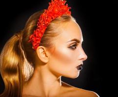 mujer de belleza con corona roja y maquillaje sobre fondo negro foto