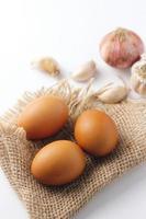 Three eggs laid on a sackcloth on a white table. photo