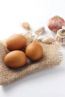 Three eggs laid on a sackcloth on a white table. photo