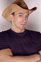 A handsome cowboy wearing a cowboy hat in a dark shirt in a studio portrait looking hot and sexy. photo