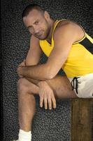un apuesto atleta joven y barbudo se estira en una pose relajada para el retrato de su deporte. foto