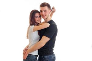charming young guy is smiling looks right and hugging beautiful girl photo