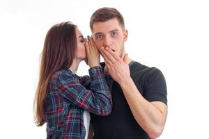 cute girl with long hair whispers a word in the ear of an amazing young guy who closed mouth hand photo