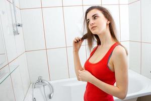 young brunette in a red vest combing her hair photo