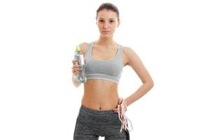 esbelta chica fitness sosteniendo una botella de agua mineral y espera foto