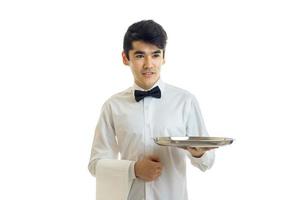 apuesto joven camarero estira la bandeja hacia adelante en la mano foto