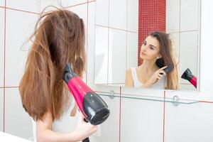 a beautiful young woman dries hair photo