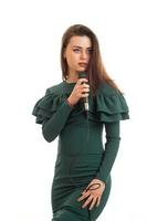 retrato vertical de una mujer hermosa con vestido verde canta un karaoke en el micrófono foto