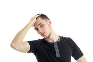 Portrait of a young guy in a black t-shirt who keeps hand behind the head photo