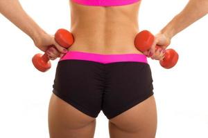 a close-up portrait of female sexual buttocks in sports shorts and with dumbbells in your hands photo