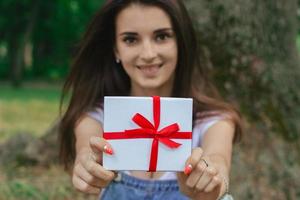 retrato de primer plano de una hermosa morena feliz con caja de regalo foto