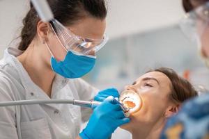 dentista y asistente tratan los dientes de un paciente foto