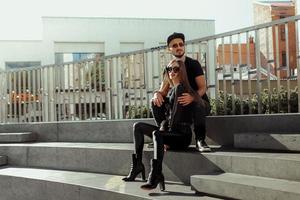 Pretty couple sits on the stairs in the street and hugs photo