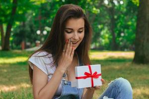 Portrait of a beautiful girl in the park with a surprised gift photo