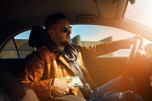 elegante modelo masculino sosteniendo un lor de dinero eur y conduciendo un coche foto