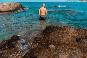 wet Guy in the blue rocky sea photo