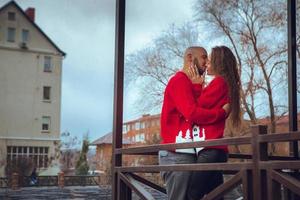 encantadora pareja apasionada se abraza en un balcón en invierno foto