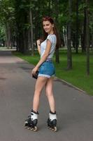 young slender girl in shorts rollerblading in the Park photo