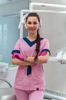 hermosa dentis en uniforme rosa sonríe en cámara foto