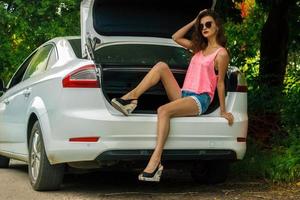 beautiful lady with bright clothes and solncezashhintyh glasses sitting of a car photo