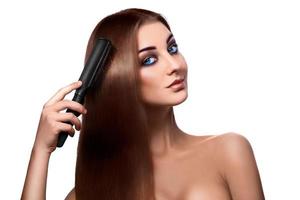 Girl combing perfect long hair and looking at camera with blue eyes photo