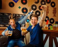 two friends drink beer in bar and have fun photo