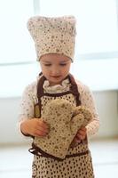 portrait of cute little homecook girl in white kitchen. photo