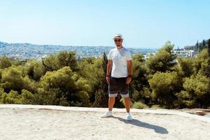 stylish guy stands above the forest on the mountain photo