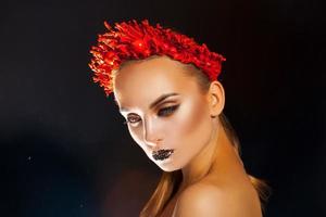 Sexual young woman with red wreath on headn on black background photo