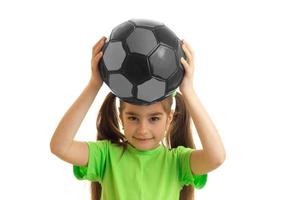 pretty little girl in green shirt with soccer ball in hands photo