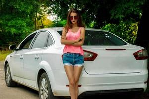 attractive girl in a bright dress posing near the white car photo