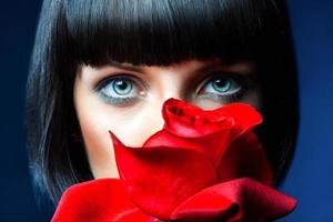 Lovely brunette behind red rose in studio photo