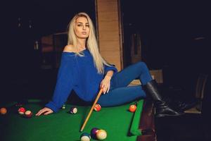 hermosa dama rubia juega al billar en la mesa de billar foto