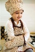 portrait of cute little homecook girl in white kitchen. photo