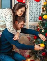 beautiful couple decorates a Christmas tree photo