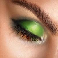 Fotografía macro de ojos cerrados con maquillaje profesional de colores verdes. foto