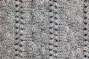 Gray knitted handmade sweater background. The texture of the surface of the woolen jersey made of yarn, close-up. Image for the background. Wool carpet or sweater. Gray texture. Modern design. photo