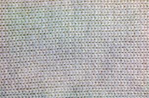 The texture of a large knit sweater or scarf. Knitted background with a relief pattern. Wool hand or machine knitting. Fabric background. photo