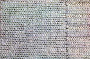 The texture of a large knit sweater or scarf. Knitted background with a relief pattern. Wool hand or machine knitting. Fabric background. photo