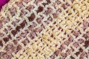 cálida bufanda de lana beige sobre un fondo lila-burdeos foto
