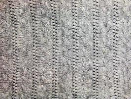 Gray knitted handmade sweater background. The texture of the surface of the woolen jersey made of yarn, close-up. Image for the background. Wool carpet or sweater. Gray texture. Modern design. photo