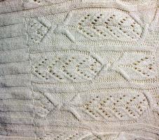 The texture of a large knit sweater or scarf. Knitted background with a relief pattern. Wool hand or machine knitting. Fabric background. photo